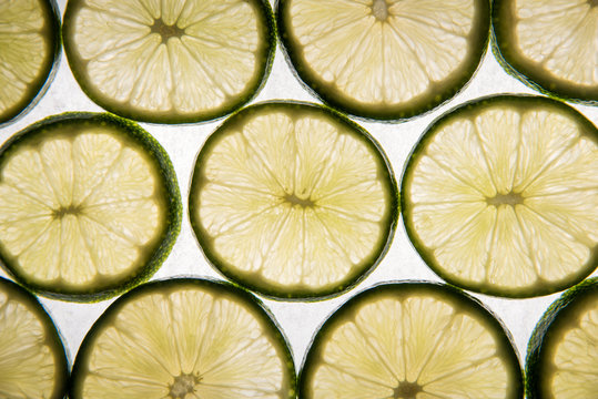 Lime slices on parchment paper, back-lit and glowing
