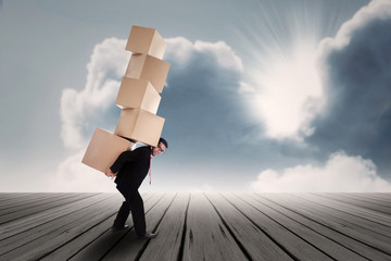 Businessman lifting many boxes outdoor