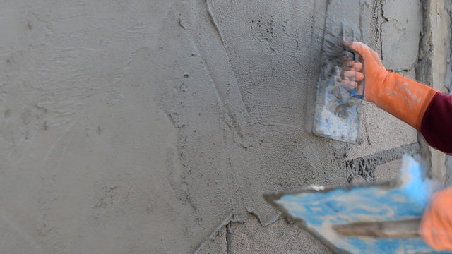 Worker plastering concrete at wall of house construction