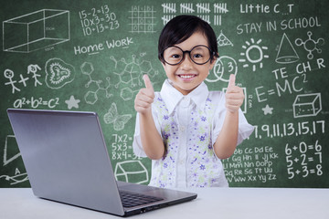 Child with laptop shows OK gesture in class