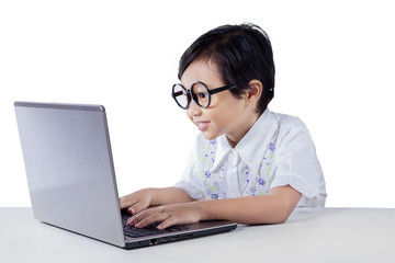 Cute little girl with glasses typing on laptop