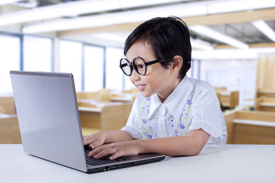 Smart child typing on laptop in the class