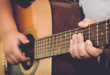 Fototapeta na wymiar finger of boy play guitar in vintage image tone.