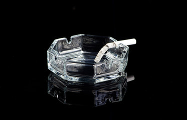 cigarette had burned down to the filter, stands on a black mirrored table