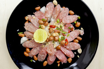 Closeup Thai sour pork sausage salad in black plate