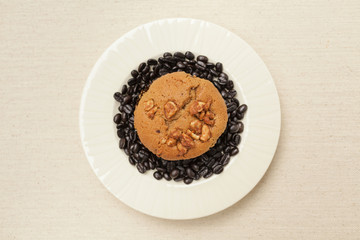 Obraz na płótnie Canvas Coffee raisin muffin with coffee bean on white plate