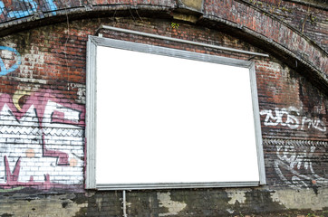 Leere Werbetafel an dunkelroter Backsteinwand mit Graffiti in urbanem Umfeld
