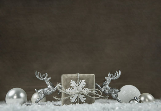 Weihnachtlicher Hintergrund in silber und wei&szlig; mit Geschenk und Holz