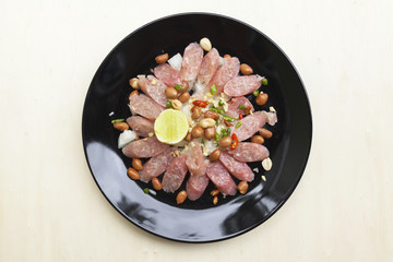 Thai sour pork sausage salad in black plate 