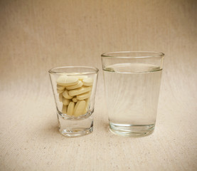 Yellow pills in glass with a glass of water
