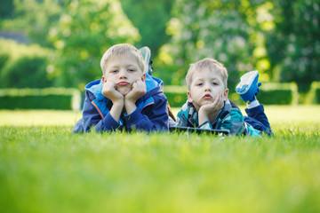 Siblings using a tablet, yingon grass in the park in suny day