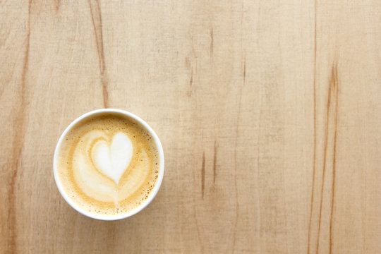 Cappuccino With Heart In Paper Take Away Cup On Light Wood Table