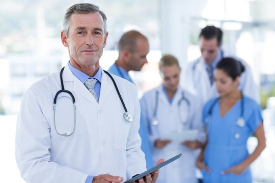 Doctor looking at camera while his colleague discussing 