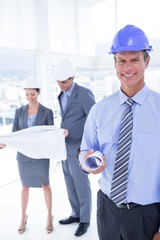 Businessmen and a woman with hard hats and holding blueprint