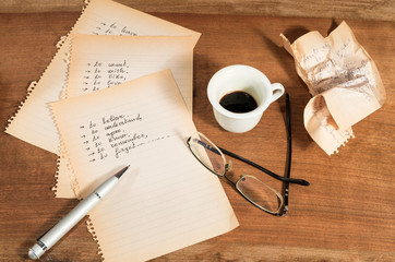 Confusione emotiva con fogli strappati,parole scritte,occhiali e tazzina di caffè semivuota sul...