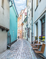 Narrow medieval street in old Riga city. Riga is the capital and largest city of Latvia, a major commercial, cultural, historical and financial center of the Baltic region
