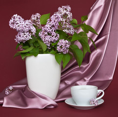 Still life with a bouquet of lilacs and a cup of tea