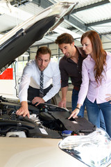 Verkäufer im Autohandel berät junges Paar beim Kauf eines Neuwagens // Couple at car dealership