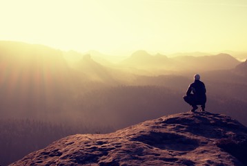 Hiker sits on a rocky peak and enjoy the mountains scenery