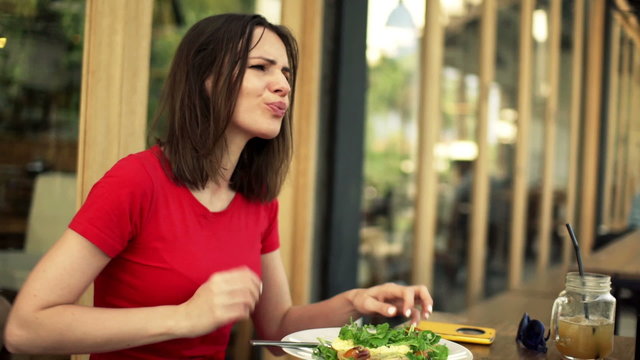 Young woman gets stomach ache during meal in cafe 
