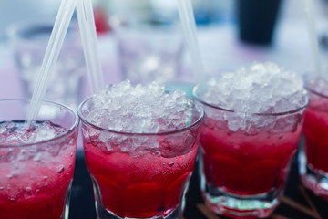 Beautiful line of different colored alcohol mojito cocktails with mint on a open air party, tequila, martini, vodka, and others on decorated catering bouquet table on open air event party.