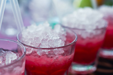 Beautiful line of different colored alcohol mojito cocktails with mint on a open air party, tequila, martini, vodka, and others on decorated catering bouquet table on open air event party.