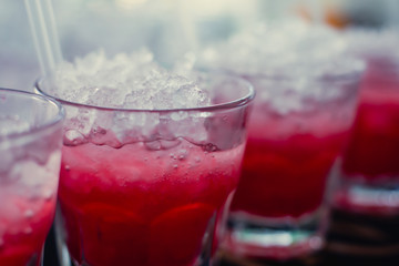 Beautiful line of different colored alcohol mojito cocktails with mint on a open air party, tequila, martini, vodka, and others on decorated catering bouquet table on open air event party.