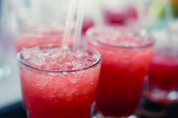 Beautiful line of different colored alcohol mojito cocktails with mint on a open air party, tequila, martini, vodka, and others on decorated catering bouquet table on open air event party.