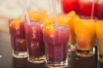 Beautiful line of different colored alcohol mojito cocktails with mint on a open air party, tequila, martini, vodka, and others on decorated catering bouquet table on open air event party.