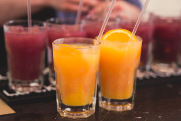 Beautiful line of different colored alcohol mojito cocktails with mint on a open air party, tequila, martini, vodka, and others on decorated catering bouquet table on open air event party.
