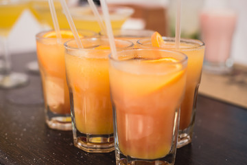 Beautiful line of different colored alcohol mojito cocktails with mint on a open air party, tequila, martini, vodka, and others on decorated catering bouquet table on open air event party.