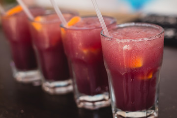 Beautiful line of different colored alcohol mojito cocktails with mint on a open air party, tequila, martini, vodka, and others on decorated catering bouquet table on open air event party.