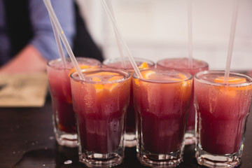 Beautiful line of different colored alcohol mojito cocktails with mint on a open air party, tequila, martini, vodka, and others on decorated catering bouquet table on open air event party.
