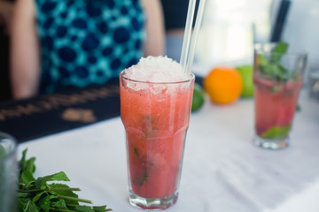 Beautiful line of different colored alcohol mojito cocktails with mint on a open air party, tequila, martini, vodka, and others on decorated catering bouquet table on open air event party.