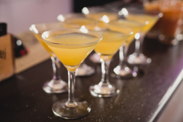 Beautiful line of different colored alcohol mojito cocktails with mint on a open air party, tequila, martini, vodka, and others on decorated catering bouquet table on open air event party.