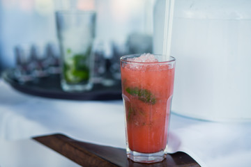 Beautiful line of different colored alcohol mojito cocktails with mint on a open air party, tequila, martini, vodka, and others on decorated catering bouquet table on open air event party.