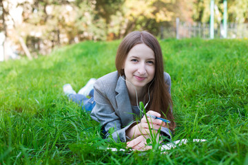 Student with headphones lying on grass