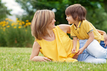 Fototapeta premium Young beautiful mom and her cute little boy, relaxing and having