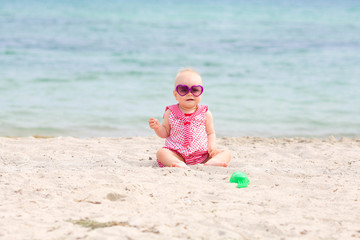 Portrait of happy baby girl in sunglasses on beach