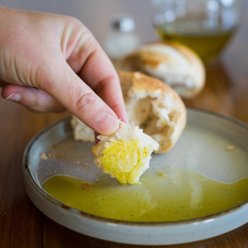 Hand with Bit of Crusty White Bread Dipped into Olive Oil. Traditional Italian Appetizer