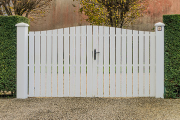 Modernes weißes PVC Tor eingebaut zwischen Hecken © Fotoschlick