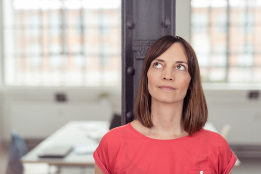 frau in einem büro schaut nachdenklich nach oben