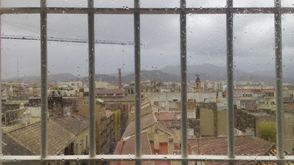 Vistas de la ciudad bajo la lluvia desee ventana con rejas
