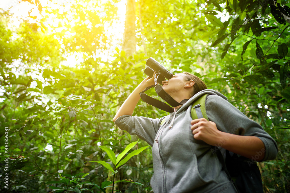 Wall mural tourist looking through binoculars considers wild birds