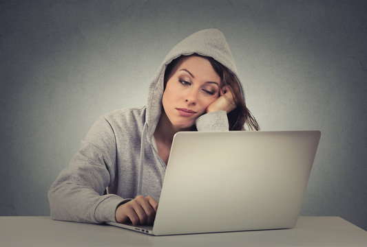 sad bored young woman using laptop sitting at table