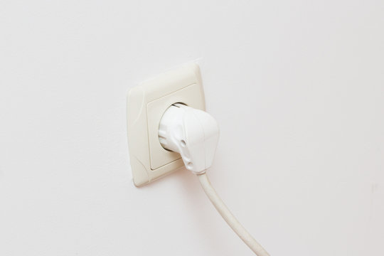 Close Up Of  Plug Into Electricity Socket on white wall