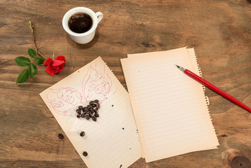 Tazzina di caffè nero con cuore di chicchi di caffè in forma di cuore alato e penna su foglio...