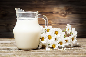 Obraz na płótnie Canvas Milk and flowers on a wooden background