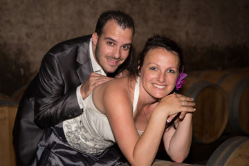 Newlywed couple in the wine cellar after their wedding looking at the camera