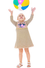 Little girl in dress throws up the ball